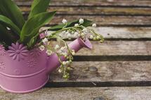 pink watering can with lily of the valley